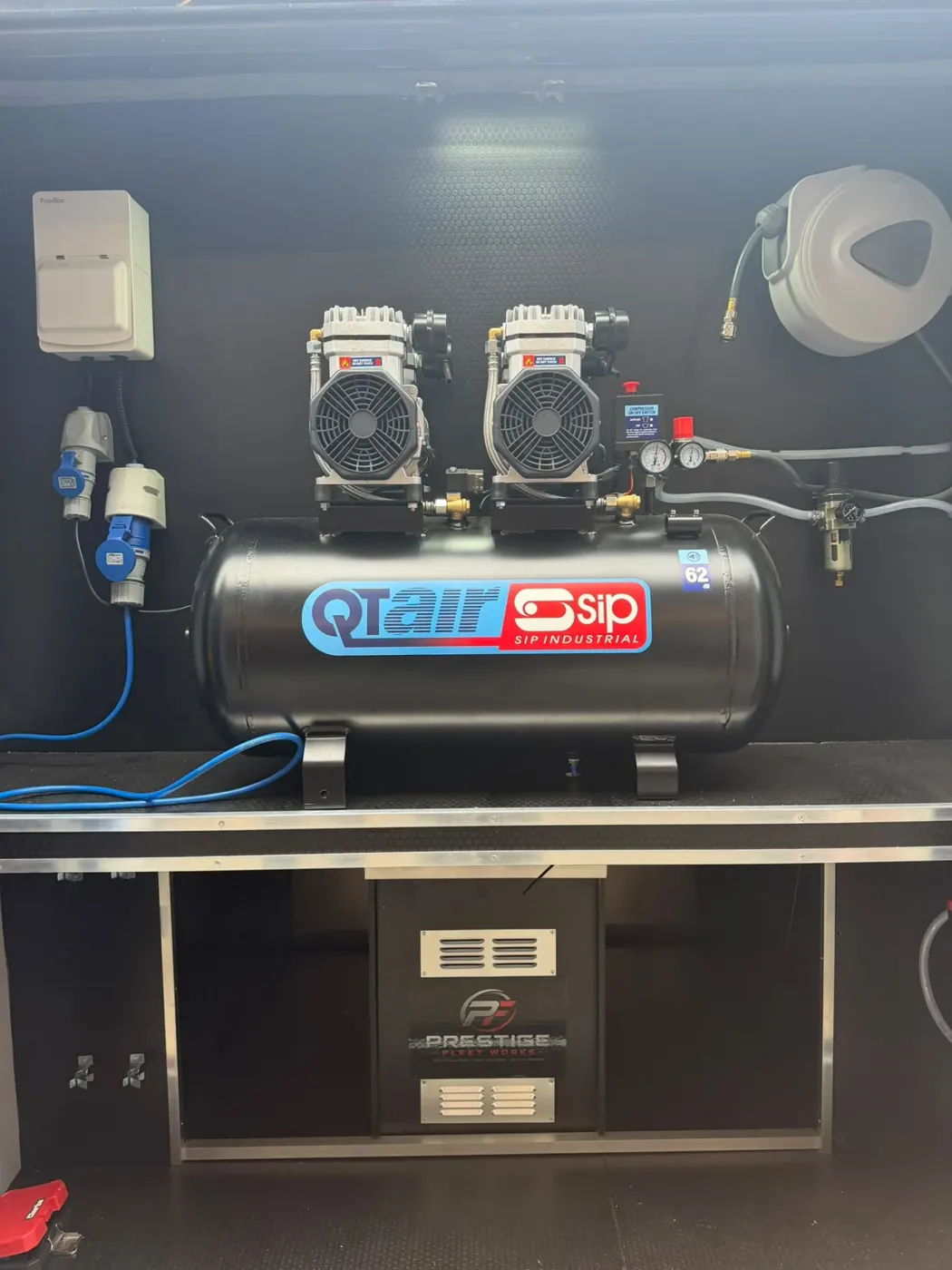 Twin-motor air compressor installed on a fitted cabinet with hose reel