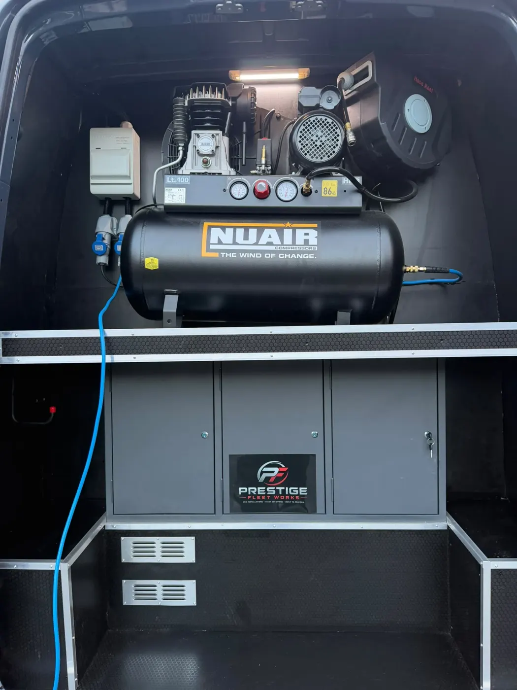 Air compressor mounted on a fitted cabinet with drawers in the rear of a van